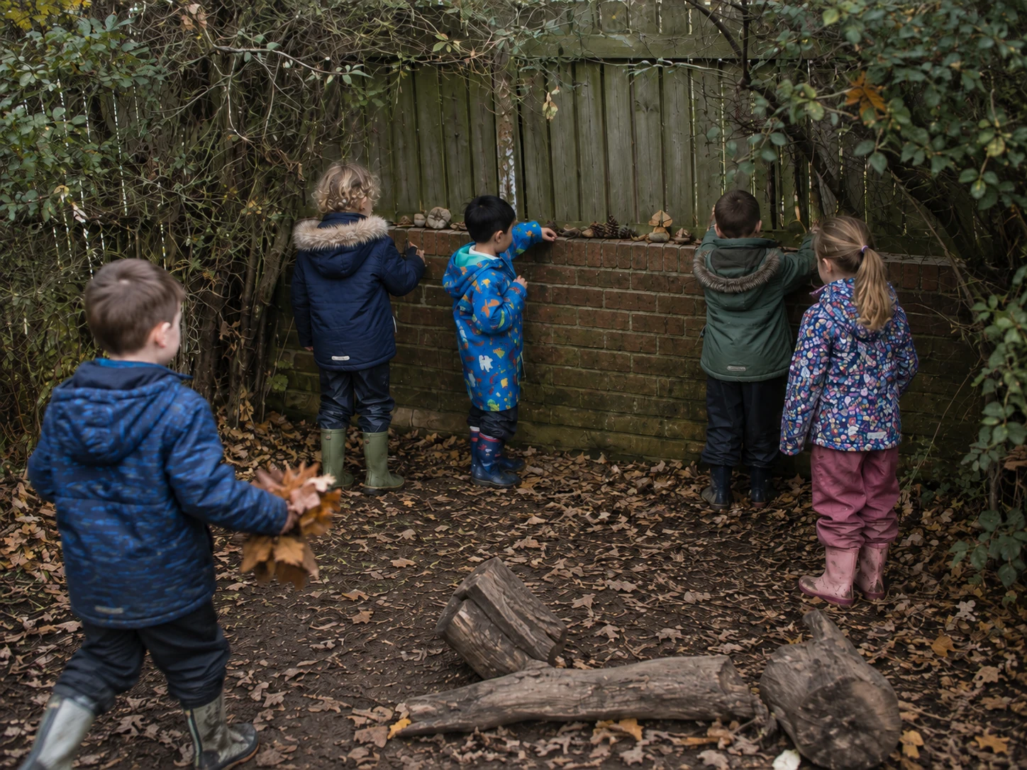 Children arranging natural objects on the ledge of their woodland shop